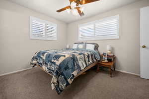 Carpeted bedroom with a ceiling fan and baseboards