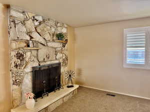 Living area featuring a stone fireplace and carpet flooring