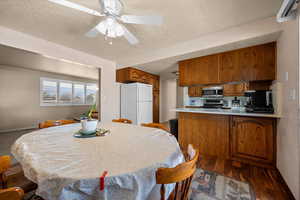 Dining room featuring ceiling fan, a textured ceiling, and dark wood finished floors