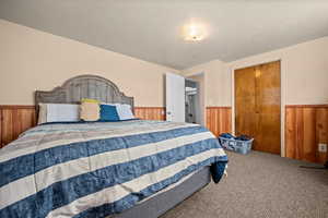 Bedroom with wood walls, wainscoting, a closet, and carpet floors