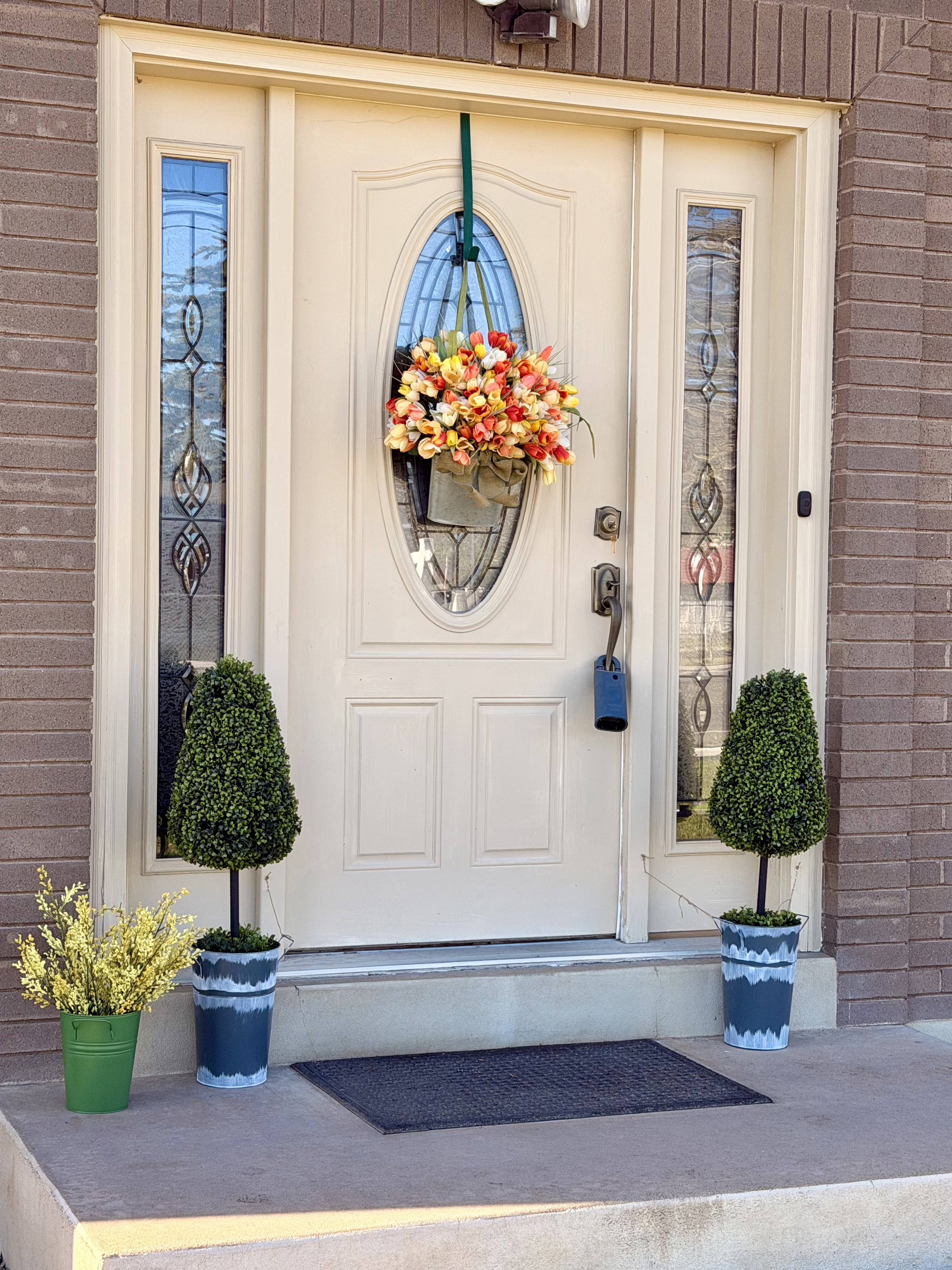 Entry door with an oval-shaped decorative glass insert, flanked by two sidelight windows featuring leaded glass