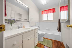 Bathroom with vanity, dark wood finished floors, and a garden tub