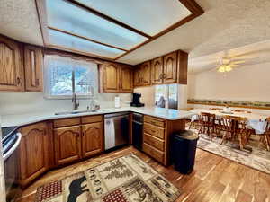 Kitchen featuring wood finish cabinetry, a textured ceiling, a peninsula, stainless steel appliances, and light wood-type flooring