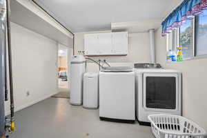 Laundry room featuring concrete floors, washer and dryer, and cabinet space