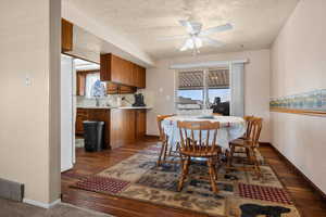 Dining space featuring dark wood-style floors, ceiling fan, and a textured ceiling