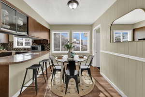 Dining room with dark wood finished floors, wooden walls, and a textured ceiling