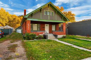 Bungalow-style house with a porch, a chimney, brick siding, and an outdoor structure