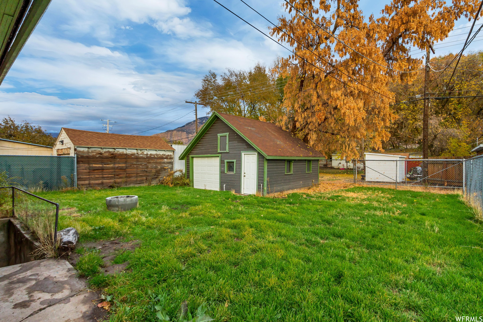 Fenced yard with a garage, an outbuilding, a gate, and an outdoor fire pit