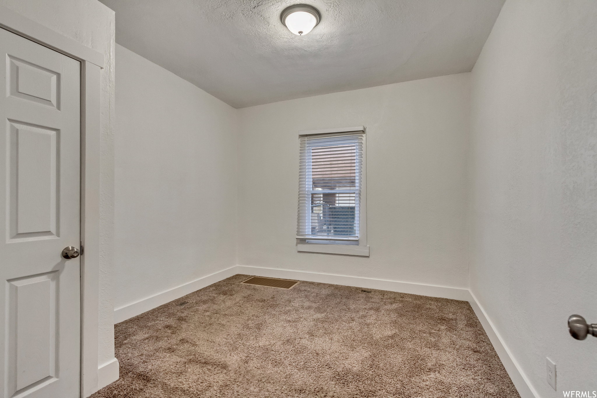 Unfurnished room featuring light colored carpet and a textured ceiling