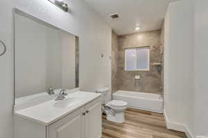 Bathroom with vanity, shower / bath combination, and light wood-style flooring