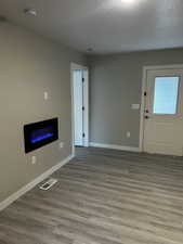 Unfurnished living room featuring wood finished floors, a textured ceiling, and a glass covered fireplace
