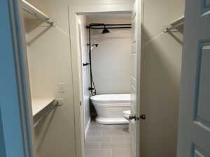 Walk in closet featuring light wood finished floors with bathroom access