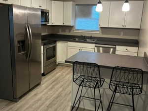 Kitchen with stainless steel appliances, a kitchen breakfast bar, a textured ceiling, hanging light fixtures, and dark countertops