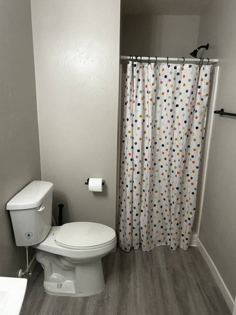 Bathroom with dark wood finished floors and curtained shower