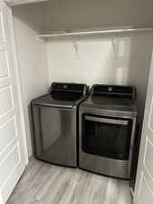 Laundry area featuring light wood-type flooring and washing machine and clothes dryer