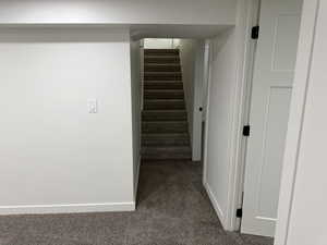 Corridor with baseboards and dark carpet