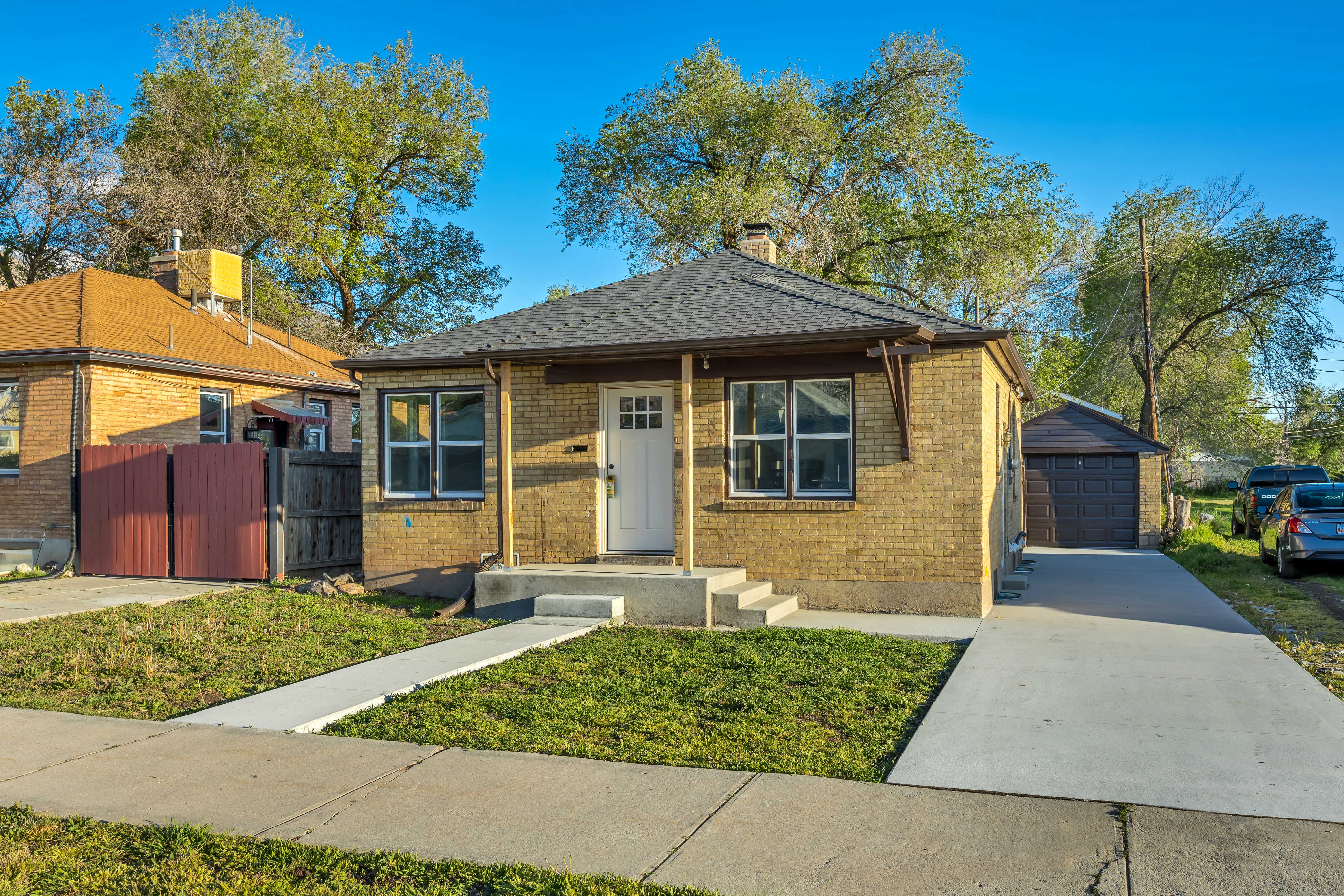 Bungalow-style house featuring an outdoor structure, a garage, brick siding, and a chimney