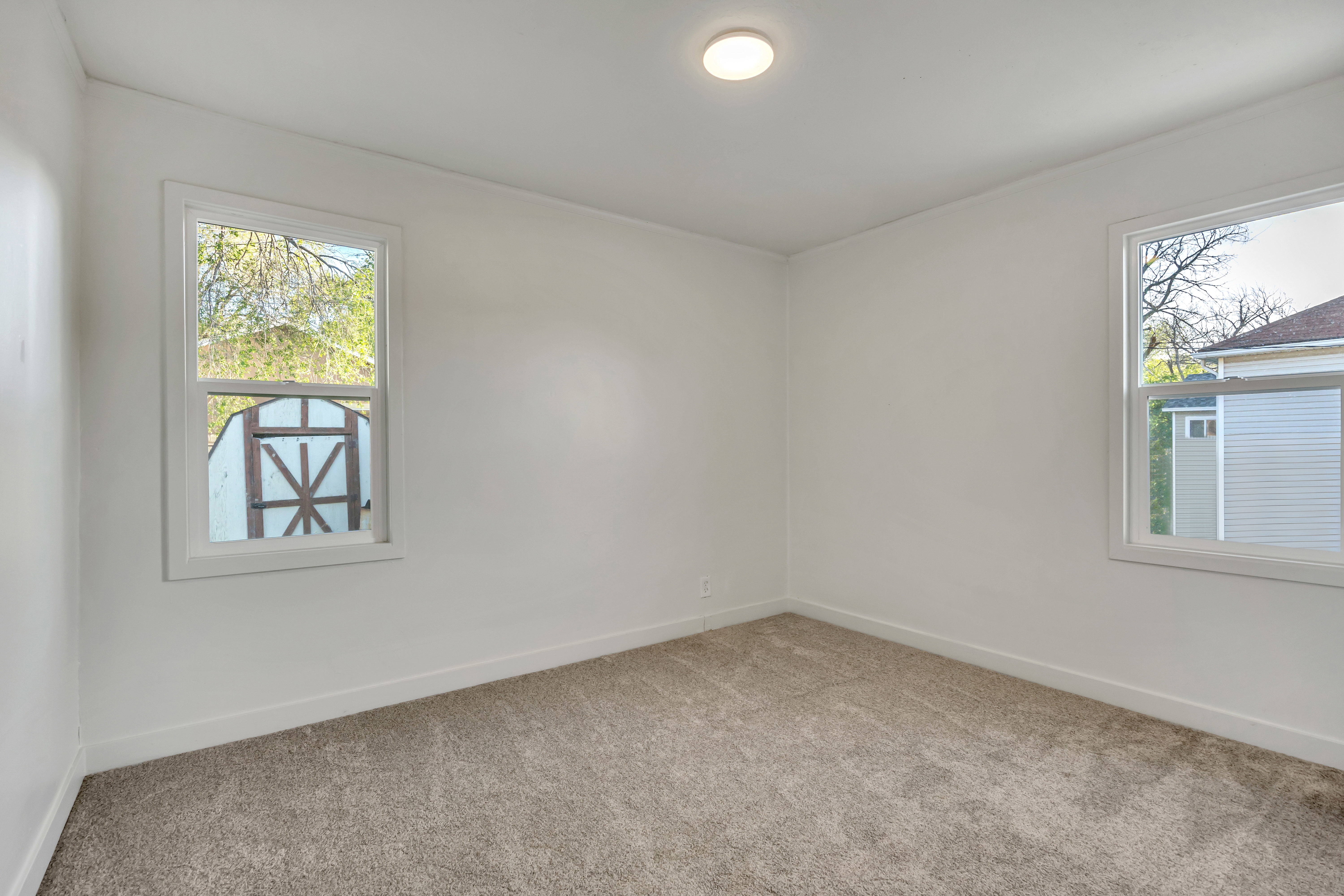 Empty room with light colored carpet and baseboards