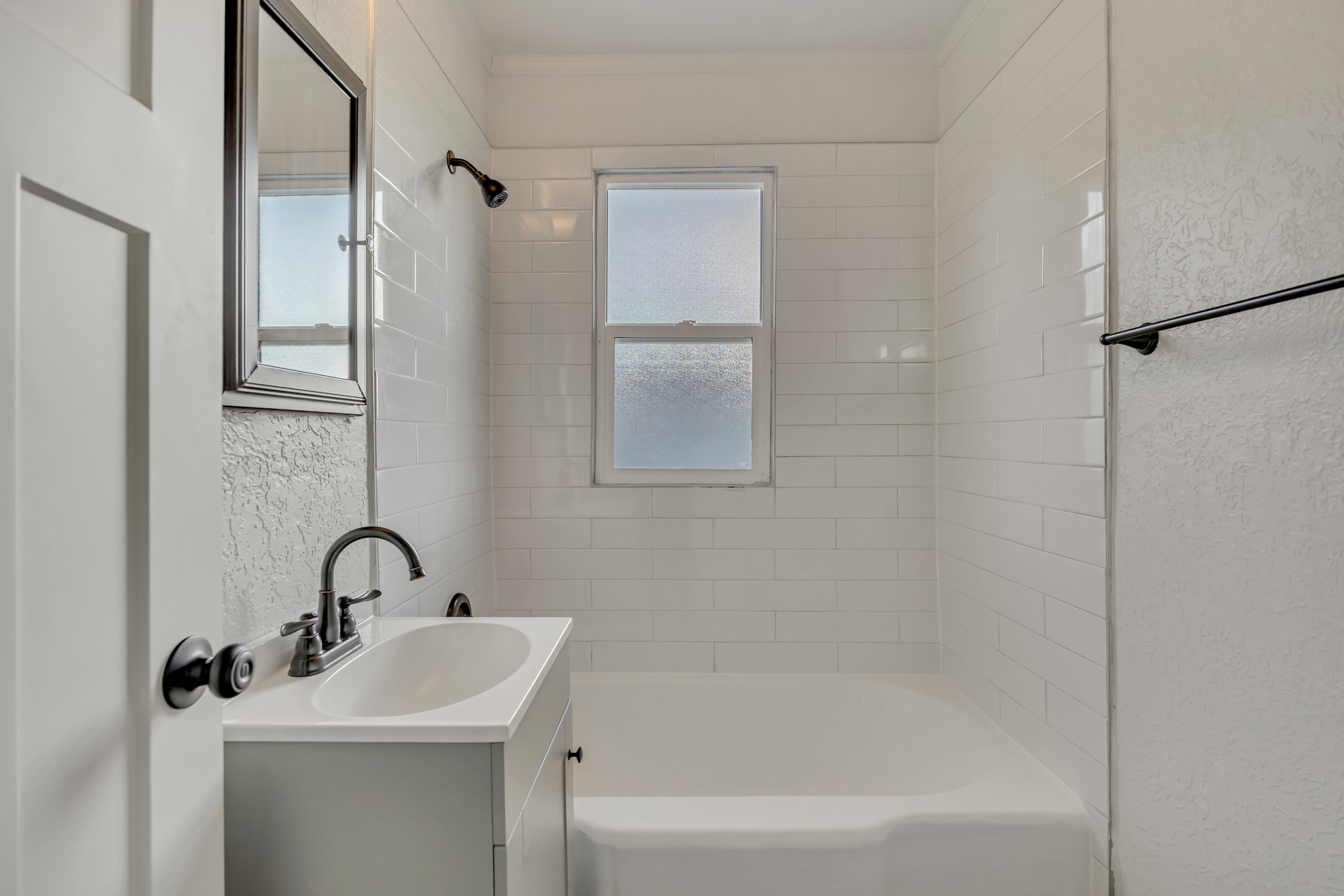 Full bath featuring vanity, a textured wall, and bathing tub / shower combination