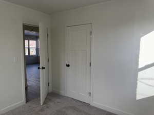 Unfurnished bedroom featuring light carpet and crown molding