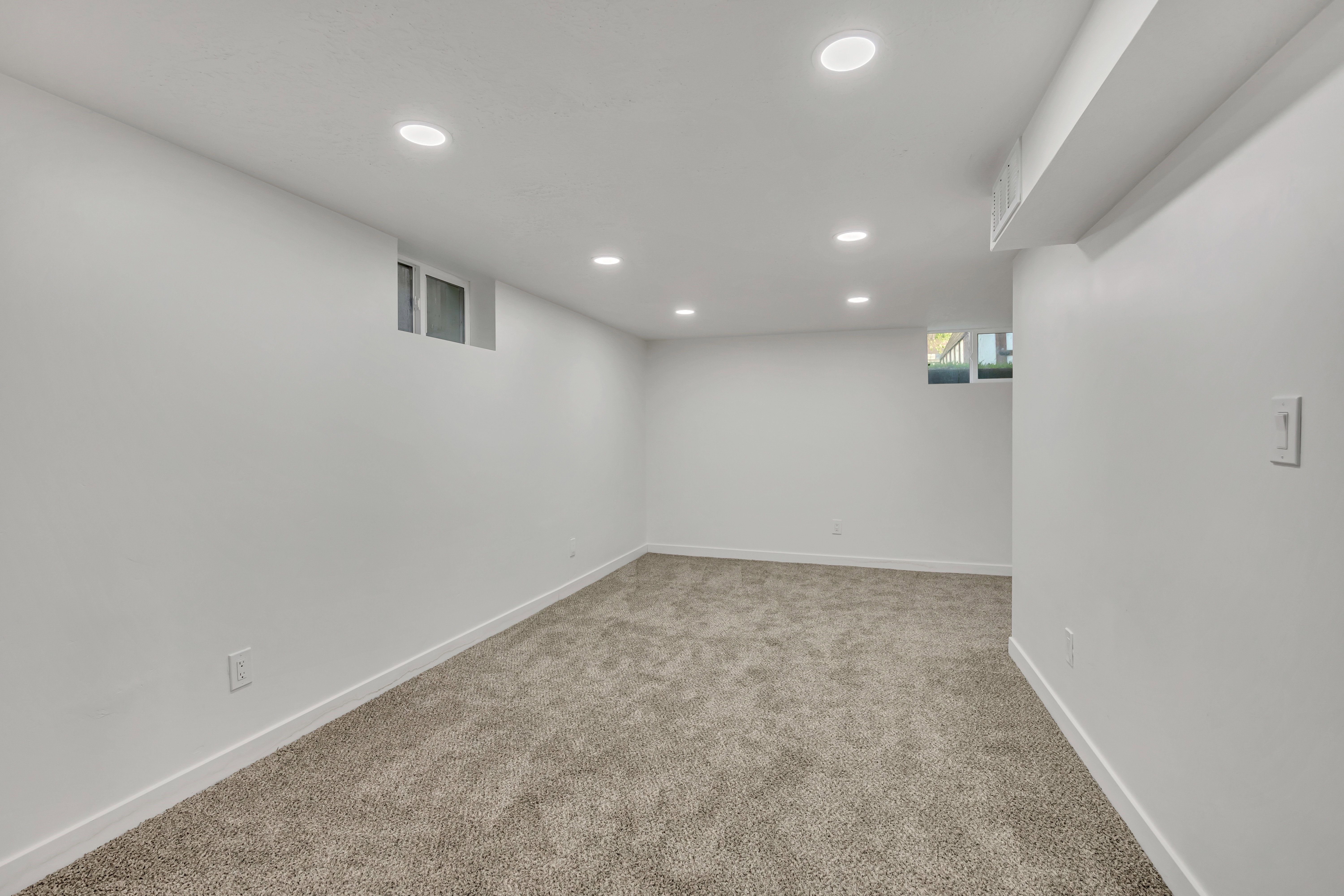 Below grade area with light carpet and recessed lighting
