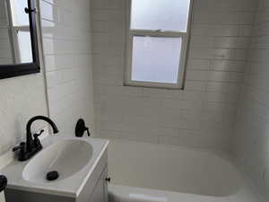 Bathroom featuring vanity, a textured wall, and tub / shower combination