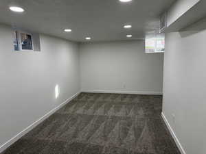 Basement featuring dark carpet, recessed lighting, and a textured ceiling