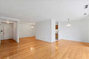 Unfurnished living room with hanging lights and light wood-style flooring
