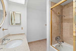 Full bathroom with bath / shower combo with glass door, vanity, and light tile patterned floors