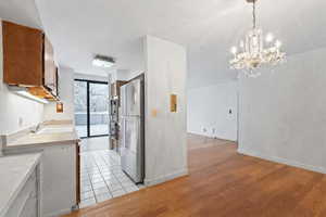Kitchen with light countertops, light wood finished floors, stainless steel appliances, wood finish cabinetry, and a chandelier