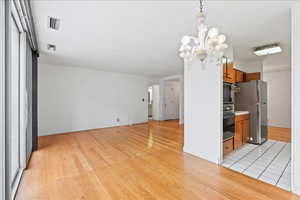 Kitchen, dining and kitchen with wood finish cabinets, light wood-style flooring, black appliances, and light countertops