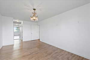 Unfurnished bedroom with hanging lights and light wood-style flooring