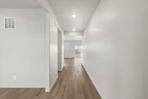 Hallway with light wood-style flooring and recessed lighting