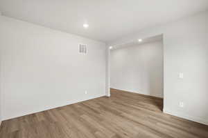 Empty room with light wood-style floors and recessed lighting