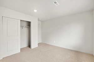 Unfurnished bedroom with light colored carpet, a closet, and recessed lighting