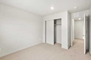 Unfurnished bedroom featuring light colored carpet and a closet