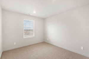 Empty room with light colored carpet and baseboards