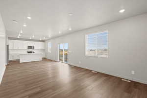 **DISCLAIMER** Interior package & colors may vary. Unfurnished living room featuring healthy amount of natural light, light wood-style flooring, and recessed lighting