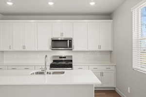 **DISCLAIMER** Interior package & colors may vary. Kitchen featuring white cabinets, stainless steel appliances, light stone countertops, recessed lighting, and dark wood finished floors