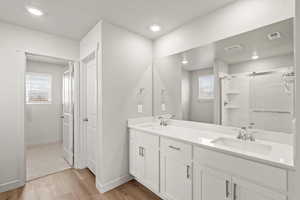 **DISCLAIMER** Interior package & colors may vary. Bathroom featuring double vanity, light wood-type flooring, a shower stall, and recessed lighting