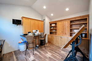 Office space featuring vaulted ceiling, light wood-type flooring, and recessed lighting