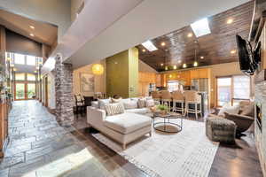 Living area with recessed lighting, a vaulted wood ceiling, stone tile flooring, a skylight, and a fireplace