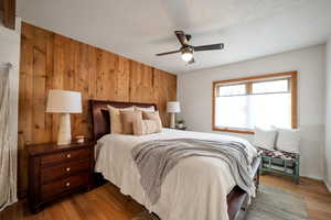 Bedroom featuring wood walls, ceiling fan, and wood finished floors