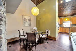 Dining space with a vaulted wooden ceiling, dark wood-style floors, and suspended lighting