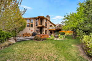 Back of property featuring a deck, outdoor dining area, a chimney, stucco siding, and a patio