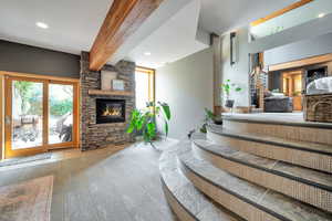 Carpeted living area with a fireplace, beamed ceiling, and plenty of natural light