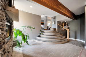 Stairway featuring beamed ceiling, a fireplace, and recessed lighting