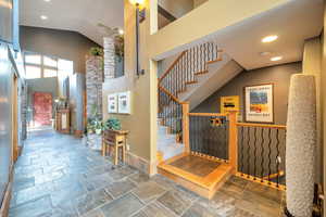 Stairway featuring recessed lighting, a high ceiling, and stone tile floors