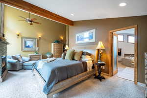 Carpeted bedroom with lofted ceiling with beams, a fireplace, and recessed lighting