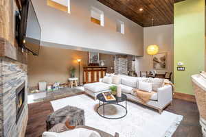 Living room with a fireplace, a high wood ceiling, and dark wood-style flooring